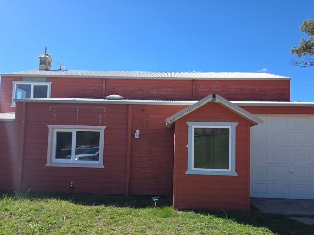 Red weatherboard exterior mid-repaint